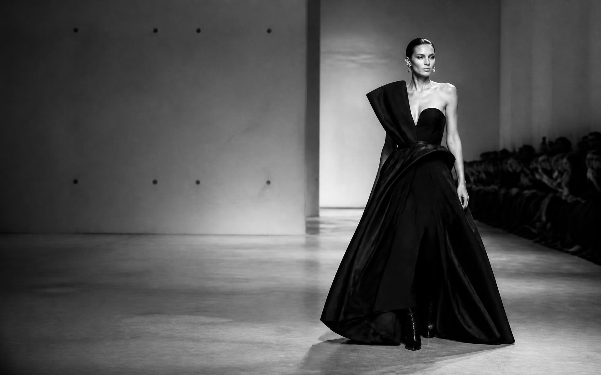 Model walking a minimalist runway in a white gallery space